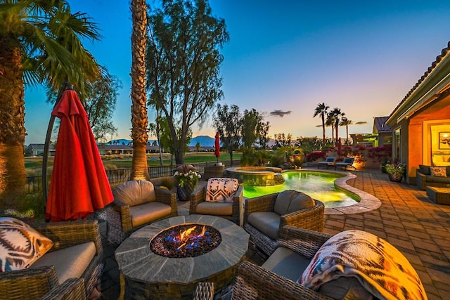 patio terrace at dusk with an in ground hot tub and a fire pit