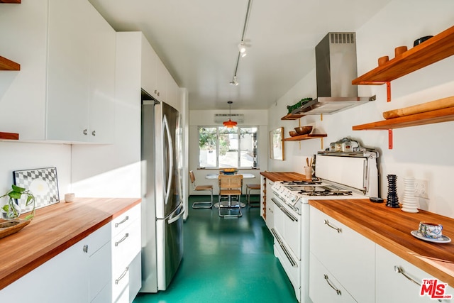 kitchen featuring pendant lighting, stainless steel fridge, white range with gas stovetop, butcher block counters, and wall chimney exhaust hood