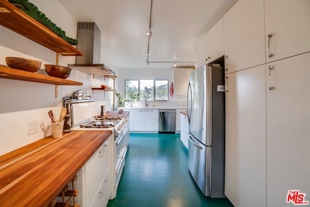 kitchen with butcher block countertops, rail lighting, white cabinetry, stainless steel appliances, and wall chimney exhaust hood