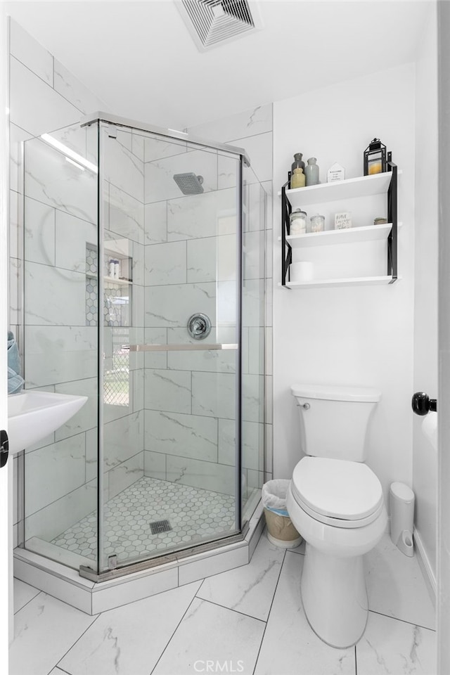 bathroom featuring a shower with door and toilet