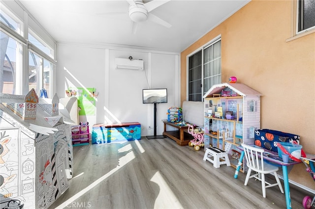 playroom with ceiling fan, hardwood / wood-style floors, and a wall unit AC