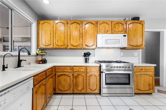 kitchen featuring white appliances, sink, and light tile patterned floors