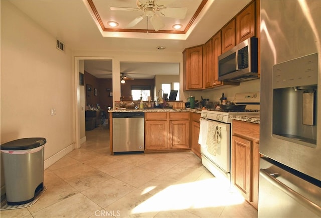 kitchen with light tile patterned flooring, ceiling fan, stainless steel appliances, and a raised ceiling