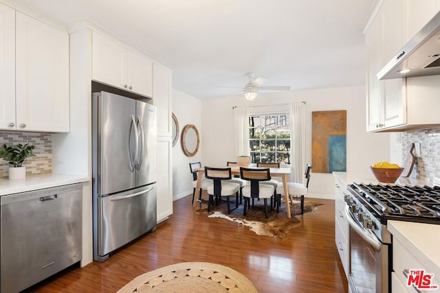 kitchen featuring range hood, white cabinetry, dark wood-type flooring, and stainless steel appliances