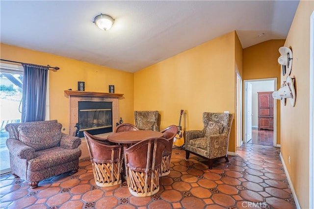 sitting room featuring a tile fireplace and vaulted ceiling