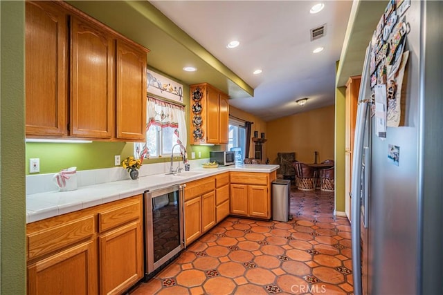 kitchen featuring lofted ceiling, sink, kitchen peninsula, tile countertops, and beverage cooler