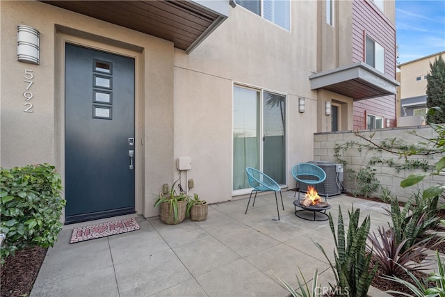 doorway to property with a patio area, central AC, and stucco siding