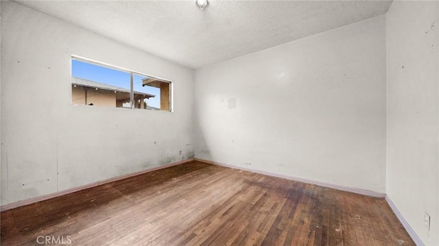 unfurnished room with wood-type flooring and a textured ceiling