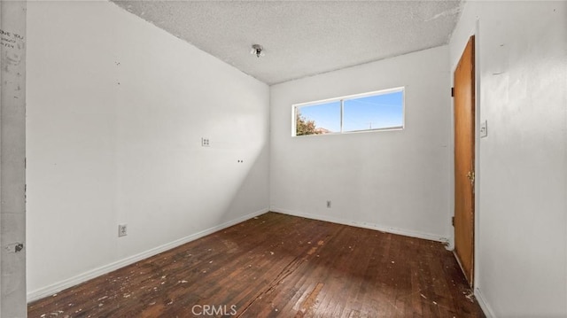 spare room featuring dark wood-type flooring and a textured ceiling