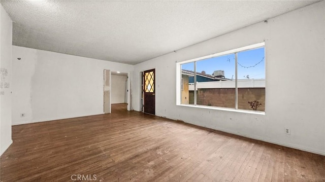 empty room with wood-type flooring and a textured ceiling