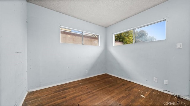 unfurnished room with hardwood / wood-style floors and a textured ceiling