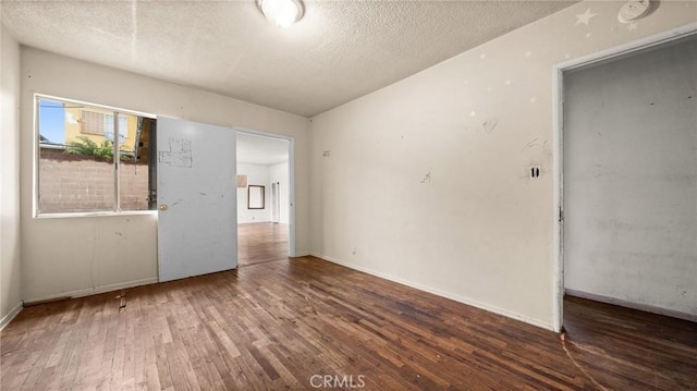 empty room with hardwood / wood-style floors and a textured ceiling