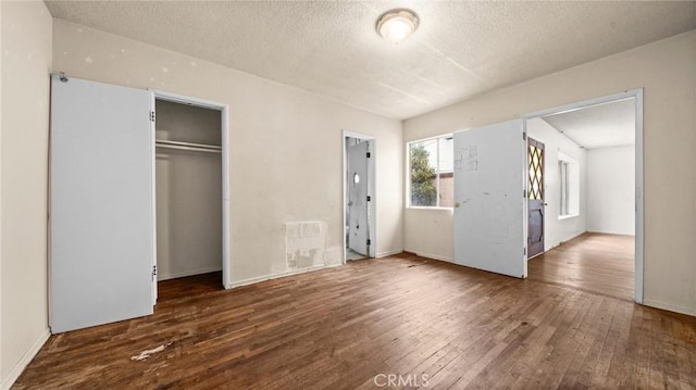 unfurnished bedroom with a closet, dark hardwood / wood-style floors, and a textured ceiling