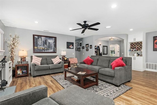 living room featuring ceiling fan, bar, and light hardwood / wood-style floors