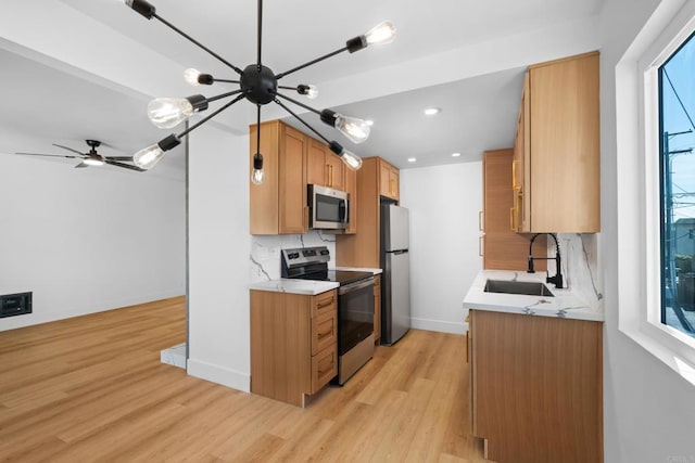 kitchen with appliances with stainless steel finishes, sink, light hardwood / wood-style flooring, and backsplash