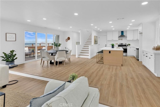 living room featuring visible vents, baseboards, stairway, recessed lighting, and light wood-style flooring