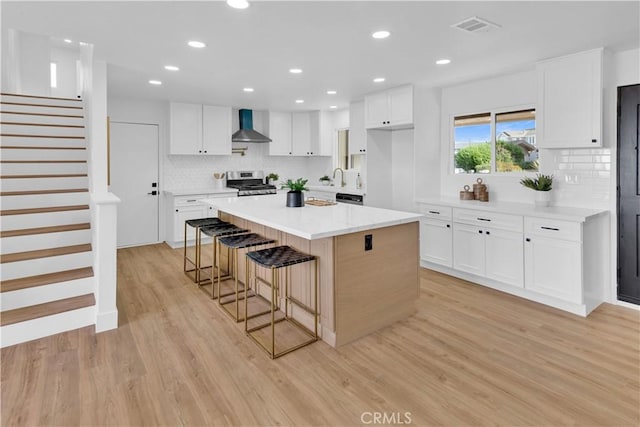 2741 Houston Dr, Los Osos, CA 93402 - kitchen featuring visible vents, light wood-type flooring, stainless steel range oven, white cabinets, and wall chimney exhaust hood