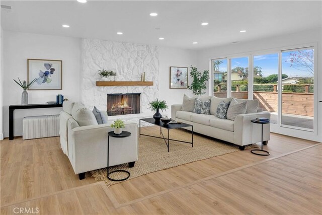 living room with radiator heating unit, a fireplace, and light hardwood / wood-style flooring