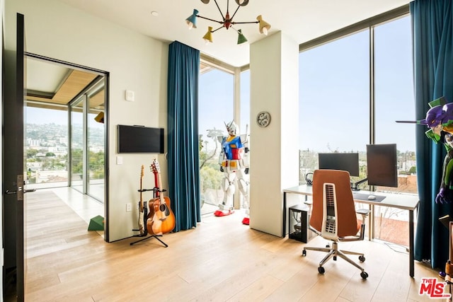 office with floor to ceiling windows, a chandelier, and light wood-type flooring