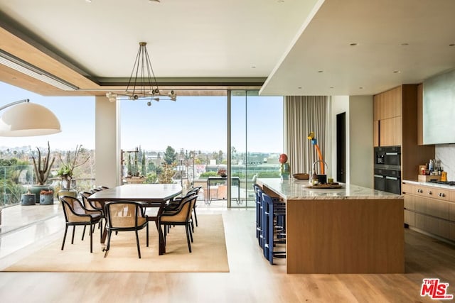 dining room featuring floor to ceiling windows, sink, and light wood-type flooring