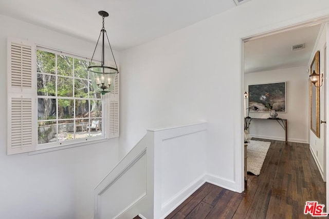 corridor with an inviting chandelier and dark hardwood / wood-style flooring