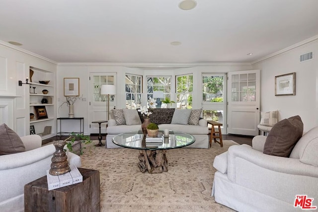 living room with crown molding, built in shelves, and hardwood / wood-style flooring