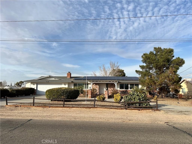 ranch-style home with a garage and solar panels