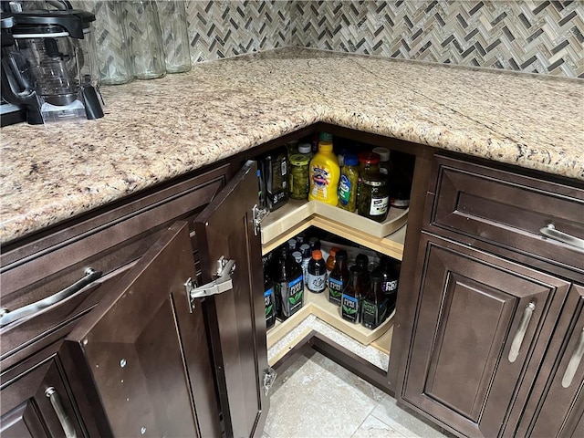 interior details featuring light stone counters, dark brown cabinets, and tasteful backsplash