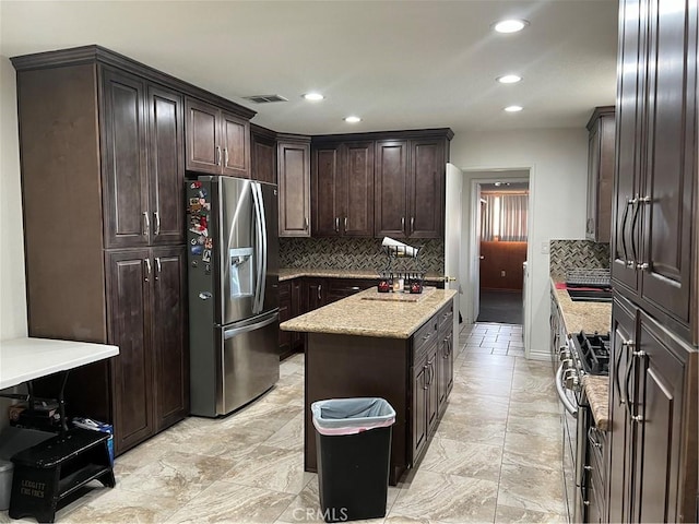 kitchen featuring tasteful backsplash, dark brown cabinets, stainless steel appliances, and a kitchen island