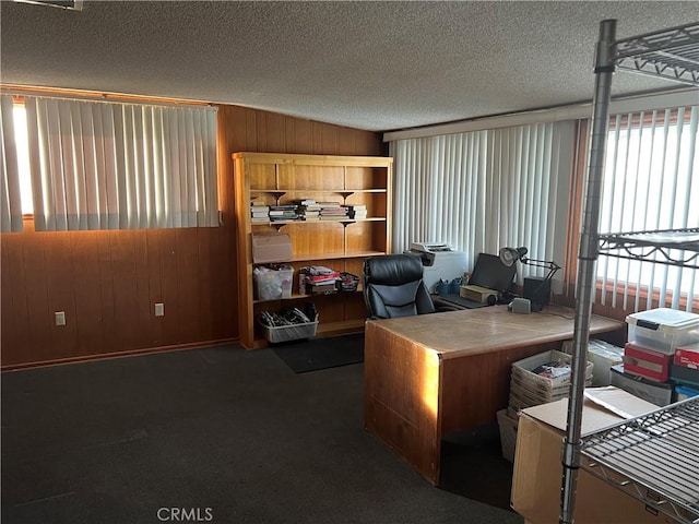 home office featuring dark carpet, a textured ceiling, and wood walls