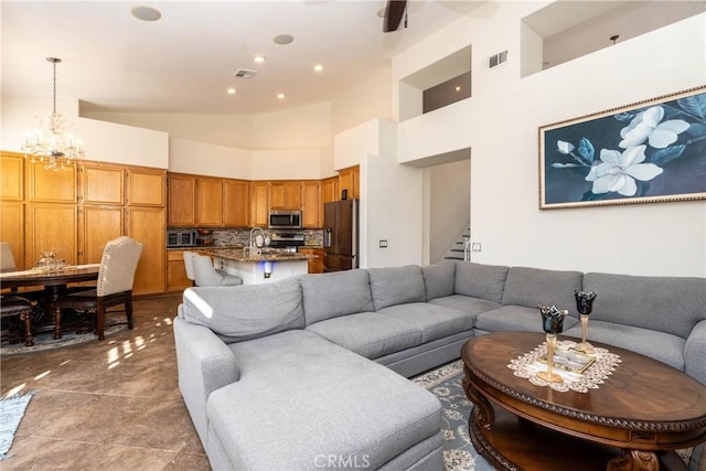 living room with a notable chandelier, sink, and a high ceiling