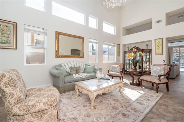 living room with a healthy amount of sunlight, a chandelier, and a towering ceiling