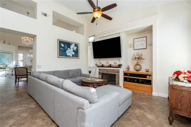 living room with ceiling fan with notable chandelier and a high ceiling