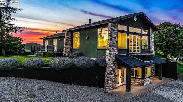 property exterior at dusk featuring french doors and a lawn