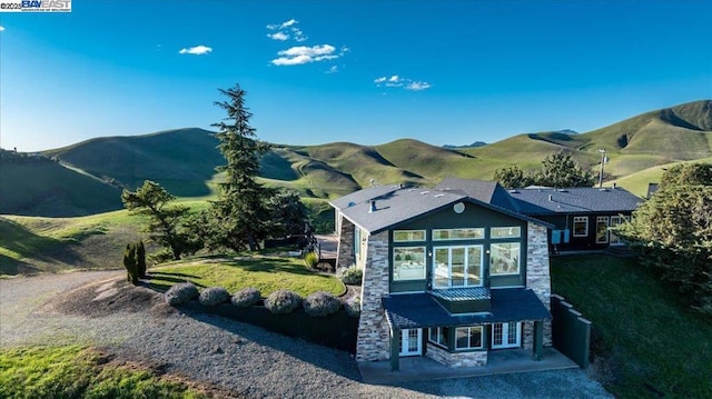 back of house with a mountain view, a yard, and a patio area