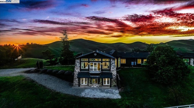 back house at dusk featuring a mountain view and a patio