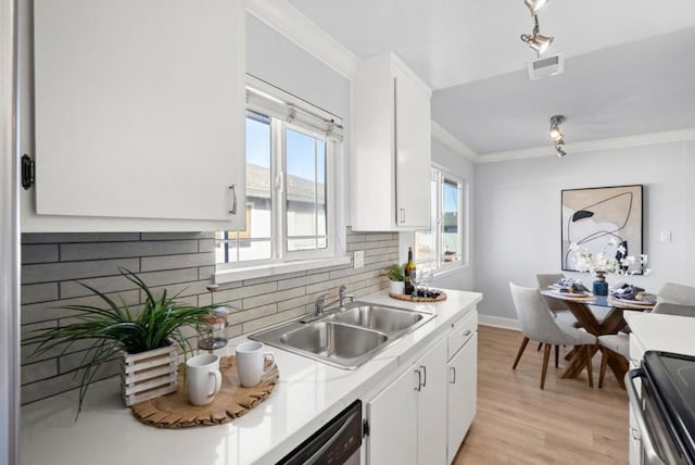 kitchen with sink, white cabinets, decorative backsplash, stainless steel appliances, and crown molding