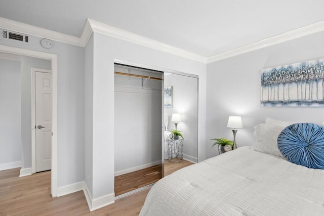 bedroom with wood-type flooring, ornamental molding, and a closet