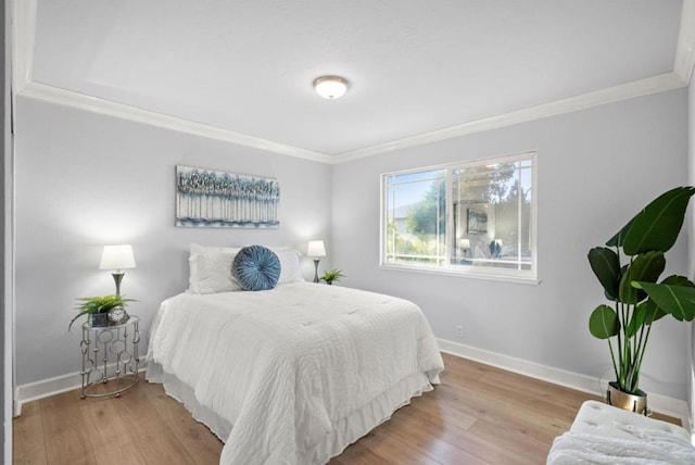 bedroom featuring crown molding and light hardwood / wood-style flooring