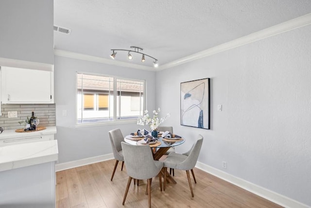 dining room with crown molding, a textured ceiling, and light wood-type flooring