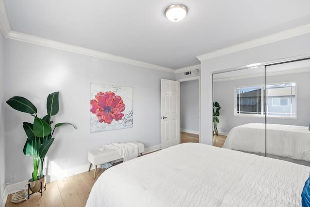 bedroom featuring wood-type flooring, ornamental molding, and a closet