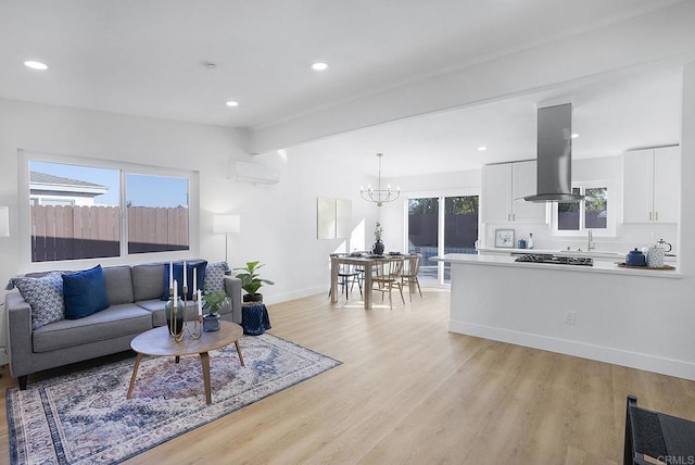 living room with sink, a chandelier, light hardwood / wood-style floors, an AC wall unit, and beamed ceiling