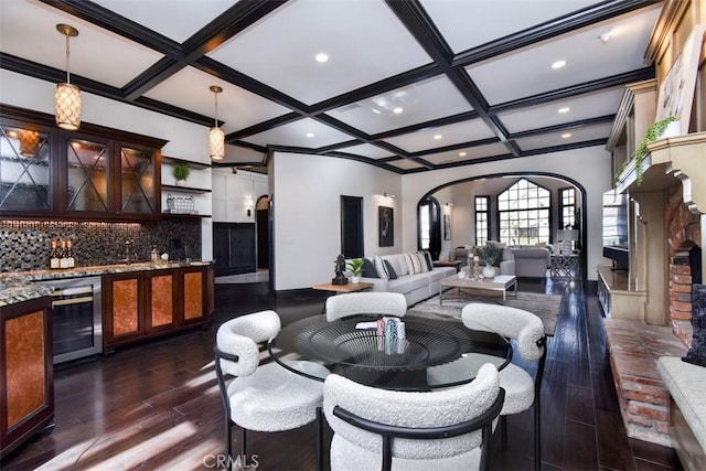 living room with coffered ceiling, dark wood-type flooring, beverage cooler, and indoor bar