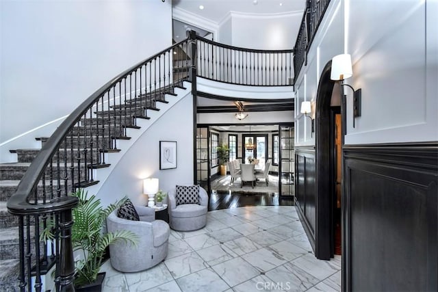 staircase featuring ornamental molding, a towering ceiling, and french doors