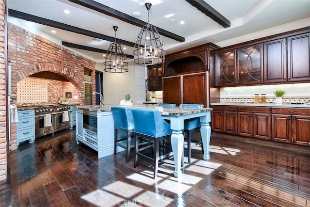 kitchen with dark wood-type flooring, dark brown cabinets, and a center island with sink