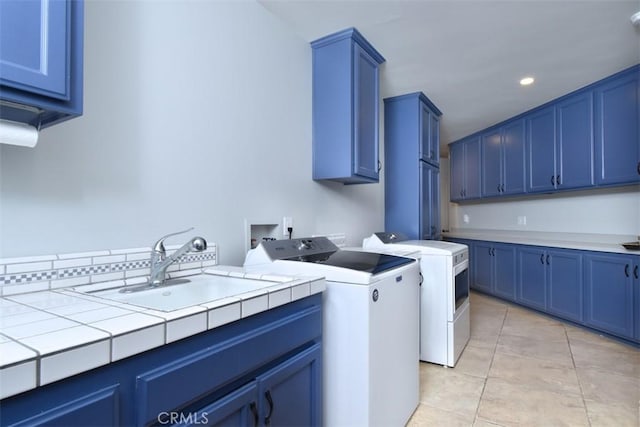 laundry room with cabinets, washing machine and clothes dryer, sink, and light tile patterned floors