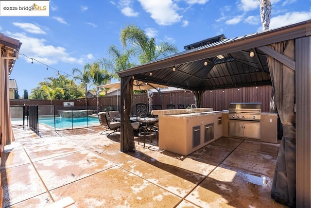 view of patio / terrace with a fenced in pool, a gazebo, grilling area, and an outdoor kitchen