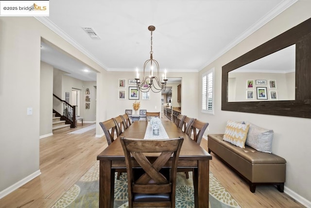 dining area featuring ornamental molding, a chandelier, and light hardwood / wood-style floors