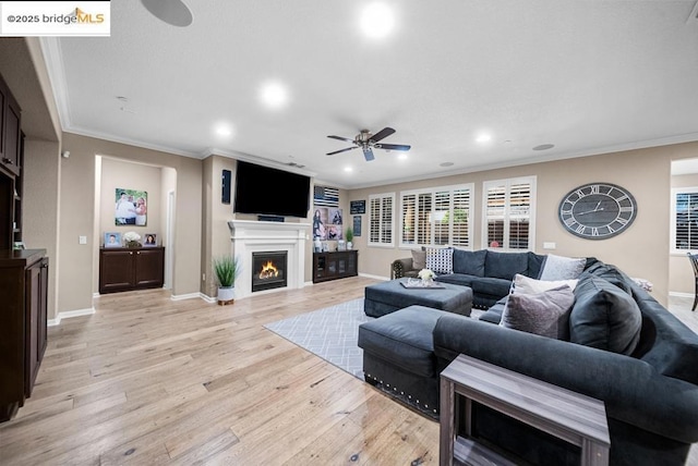 living room with crown molding, ceiling fan, and light wood-type flooring