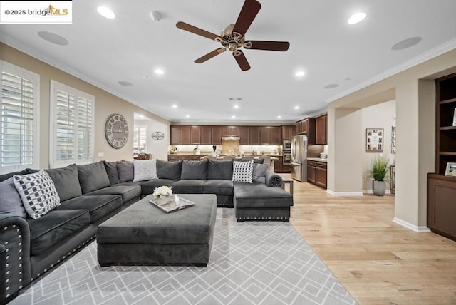 living room featuring crown molding, ceiling fan, and light hardwood / wood-style floors